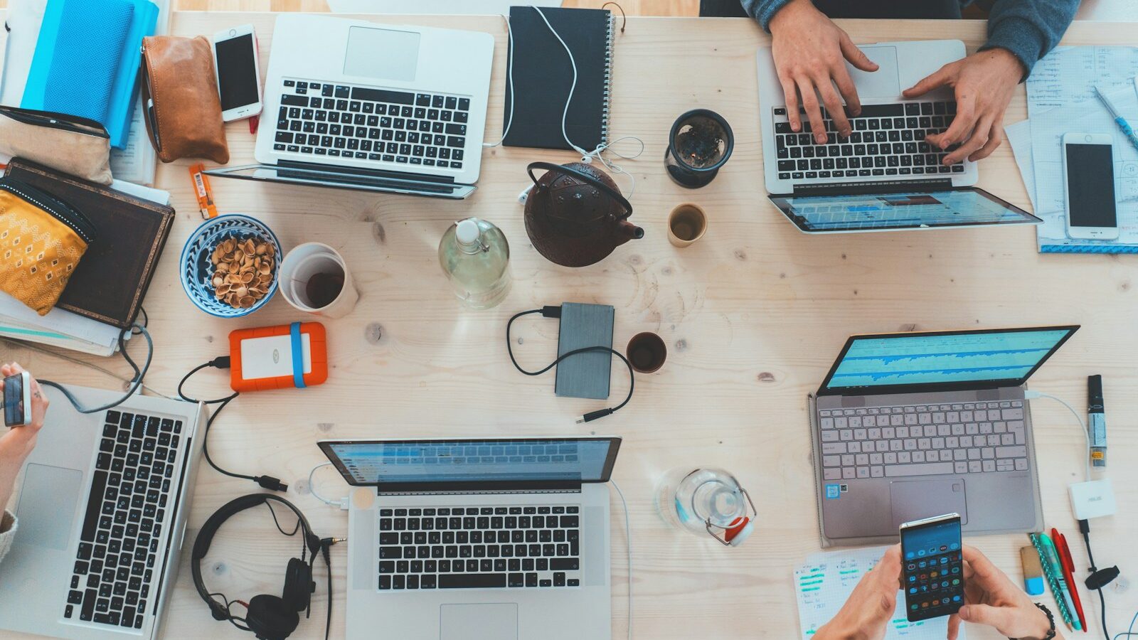 people sitting down near table with assorted laptop computers